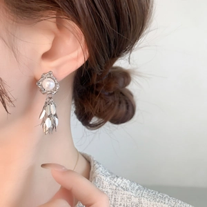 Detail of silver leaf fringe earrings with pearls worn with a grey tweed jacket
