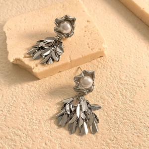 Detailed close-up of silver leaf tassel earrings with white pearls on a stone base