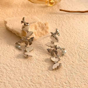 Dettaglio macro di orecchini a farfalla in argento con inserti in madreperla e zirconi