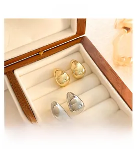 Detailed view of teardrop earrings in polished gold and silver finish inside a box
