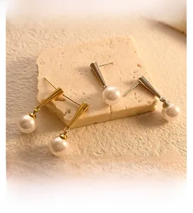 Detailed view of long drop earrings with polished metal cones and round white pearls