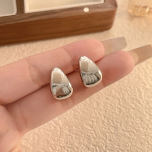 Detailed view of polished silver water drop earrings held by hand for size reference