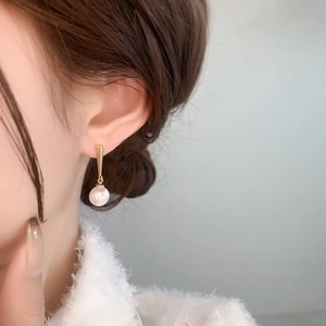 Close-up of elegant 18K gold plated drop earrings with lustrous white pearls on a model