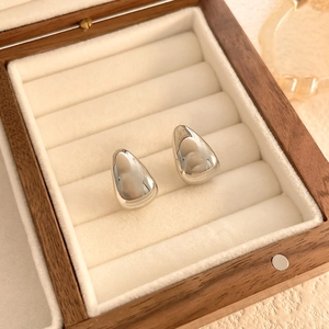 Close-up of polished silver teardrop stud earrings in a luxury jewelry box display