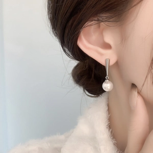 Close-up of a model wearing minimalist pearl drop earrings with 18K gold plated metal