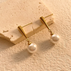 Detailed view of high-gloss pearl earrings with 18K gold-plated conical studs on stone