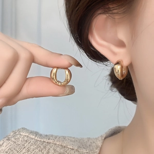 Minimalist gold hoop earrings with brushed texture shown on model in close-up shot