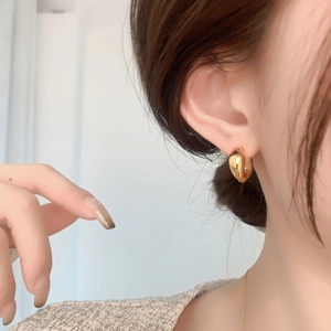 Close-up of elegant wide golden hoop earrings with polished mirror finish on model