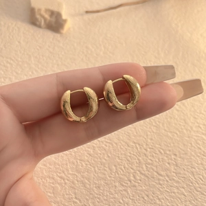 Close-up of golden hoop earrings with textured finish and snap closure detail