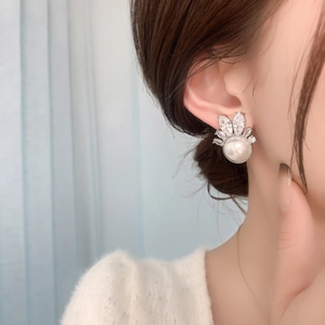 Detailed close-up of crown-shaped earring with white pearl and sparkling zircon stones