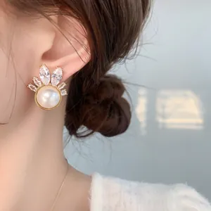 Detail of elegant gold earrings with white pearl and marquise zircon on a model