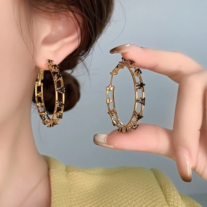 Orecchini a cerchio dorati con stelle mostrati sulla modella per stile e dimensioni