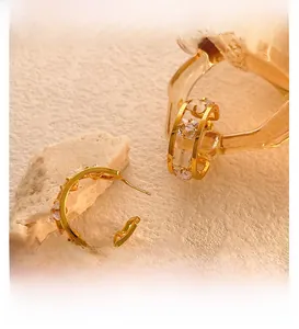 Detailed macro view of gold-plated C-shaped earrings with square-cut cubic zirconia