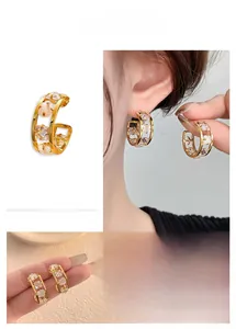 Detail of C-shaped earrings with square zircons and opals in a gold-plated vintage style