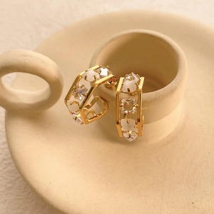 Macro shot of hexagonal gold earrings with pavé zircons and opal on a ceramic base