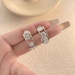 Detail view of silver geometric earrings with micro-pave cubic zirconia on hand