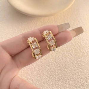 French style square earrings with white opal and cubic zirconia held by hand