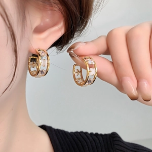 Golden C-shaped hoop earrings with purple cubic zirconia and hollow geometric patterns