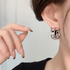 Macro detail of geometric silver hoop earrings with square cubic zirconia on a model