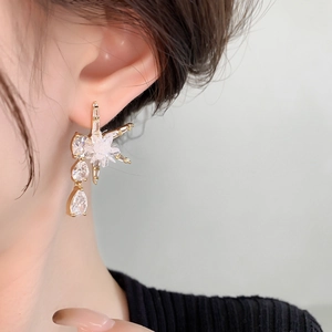 Détail de boucles d'oreilles étoiles avec pampilles dorées et pierres en zircon taille poire