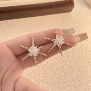 Gros plan de boucles d'oreilles étoile dorées 18K ornées de zircons étincelants