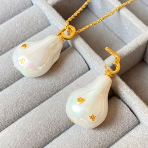 Gros plan d'un pendentif perle baroque sur une chaîne torsadée en or pour ensemble bijoux