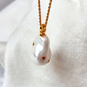 Détail du pendentif en perle baroque avec fleurs dorées sur chaîne torsadée