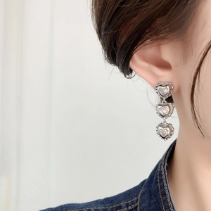 Close-up of vintage silver triple heart drop earrings with sparkling zircon inlay