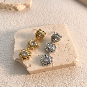 Close-up of triple layered gold heart dangle earrings with sparkling cubic zirconia crystals