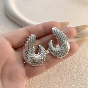 Dettaglio macro di orecchini d'argento con trama a spirale per mostrare dimensioni e luce
