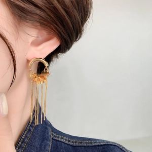 Detail of gold tassel earrings with hanging chains and sequins on a model