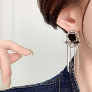 Detailed close-up of long silver chain tassel earrings on model in blue denim outfit