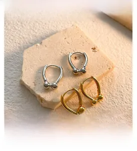 Detail of U-shaped horseshoe earrings in gold and silver finish on stone display