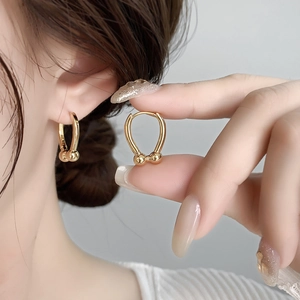 Minimalist golden U-shaped horseshoe earrings with double beads shown on ear