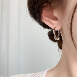 Close-up of minimalist silver horseshoe earrings with metal bead accents for women