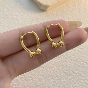 Minimalist gold U-shaped hoop earrings with dual ball charms shown in hand for scale