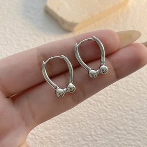 Detail of silver U-shaped horseshoe hoop earrings with double beads on model hand