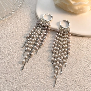 Détail de boucles d'oreilles à pompons argentés avec perles roses et chaînes fines
