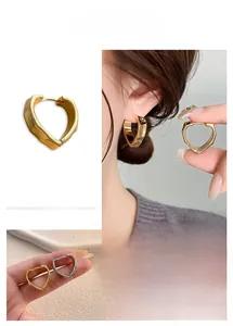 Close-up of geometric heart hoop earrings with irregular mirrored surface in gold and silver