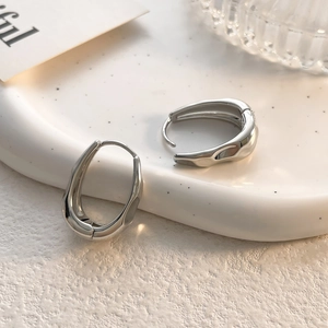 Detail of silver irregular lava earrings on white terrazzo tray with aesthetic props