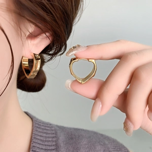 Elegant gold heart shaped hoop earrings with polished finish shown on a female model