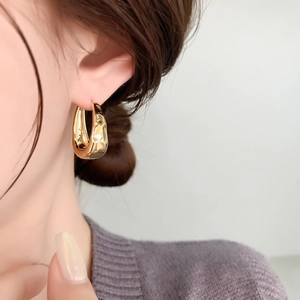 Close-up of chunky gold hoop earring with irregular hammered texture on model ear