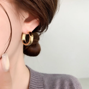 Close-up of model wearing thick gold hoop earring with mirror polished finish