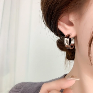 Close-up of silver mirror-polished wide hoop earrings on model with high gloss finish