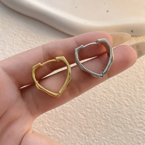 Macro view of gold and silver heart-shaped hoop earrings with irregular lava texture
