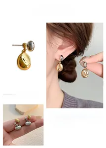 Detail view of stylish gold and silver bean-shaped earrings with reflective metallic finish