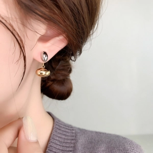 Macro detail of mixed-metal drop earrings featuring gold and silver polished spheres