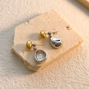 Detail of two-tone gold and silver bean earrings showing mirror polish and honeycomb texture