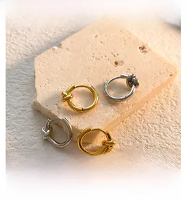 Close-up of geometric knotted hoop earrings in gold and silver finish on stone