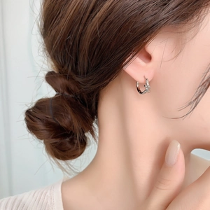 Close-up of minimalist silver knot hoop earrings worn on a model's ear for a stylish look